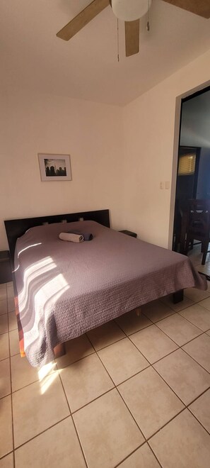 A bedroom with a bed, a ceiling fan, a framed picture on the wall, and a view of the outside through a door. - Marina Loft Condos №214, 2 floor № 214 (Coco)