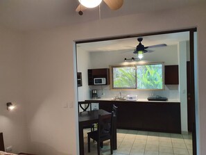A compact kitchen with a microwave, coffee maker, and a window with blinds. - Marina Loft unit 103  1 floor (Coco)