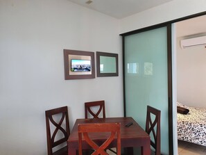 A room with a dining table and chairs, a bed with patterned bedding, and two framed pictures on the wall. - Marina Loft Studio # 207 (Coco)
