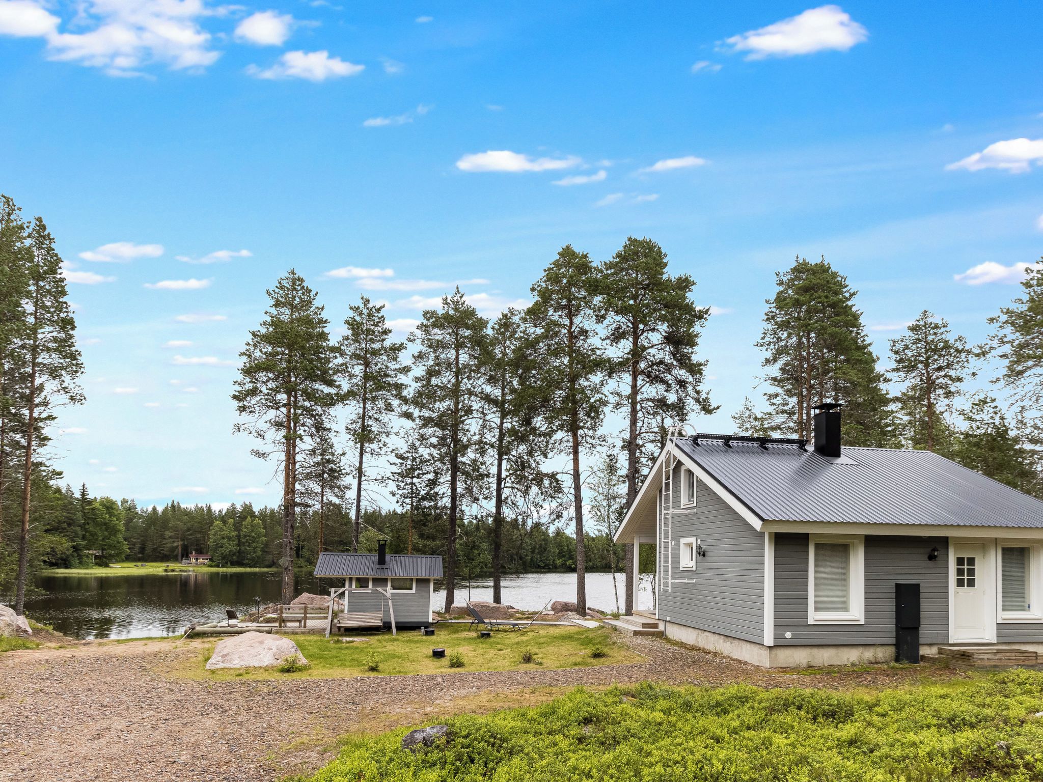 Mökki, jossa on laituri, ja sen ympärillä on metsää ja järvi.