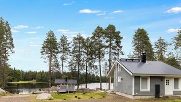 Mökki, jossa on laituri, ja sen ympärillä on metsää ja järvi.