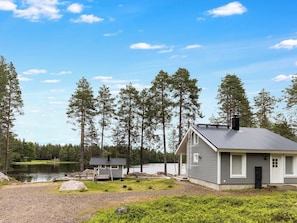 A cabin with a dock, surrounded by a forest and a lake.