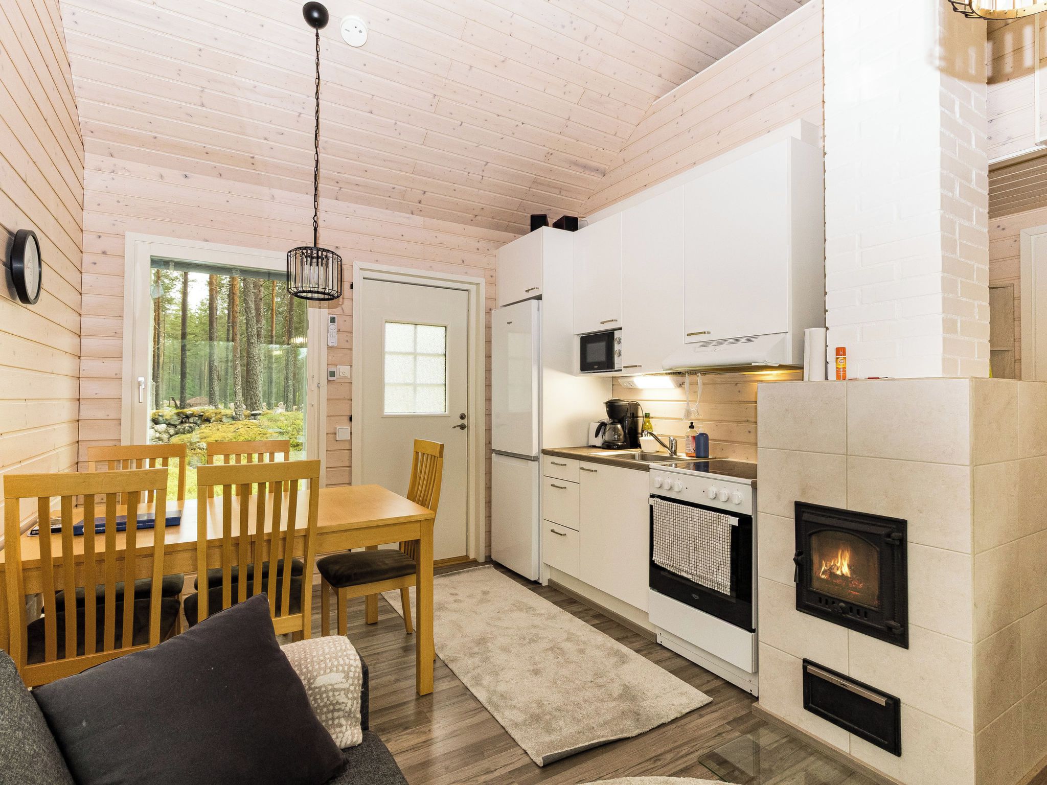 Interior acolhedor de uma cabana, com sala de jantar, cozinha e lareira.