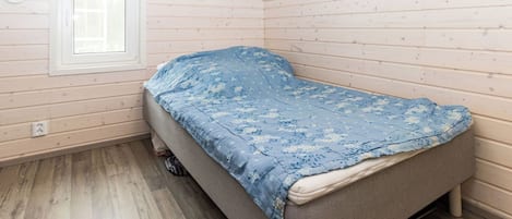 A single bed in a room with wooden walls and a sloped ceiling.