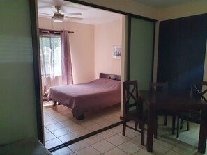 A bedroom with a bed, a chair, a table, and a ceiling fan. - Marina Loft Studio # 218 (Del Coco Beach)