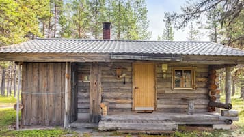 A rustic cabin with a wooden exterior, a tiled roof, and a front porch.