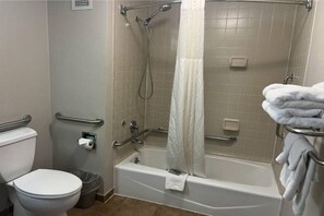 Un baño con inodoro, ducha con puerta de vidrio y bañera.