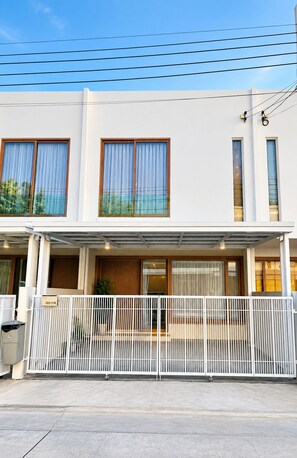 Un edificio moderno a due piani con ingresso coperto e viale recintato.