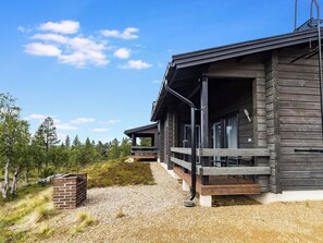 Ein modernes Blockhaus mit einer überdachten Veranda und einer Schotterauffahrt.