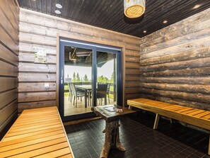 A wooden interior with a bench, a table, and a glass door leading outside. - Villa polar night by Interhome (Inari)