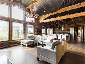 A spacious living area with a large sectional sofa, a fireplace, and a view of the outdoors through large windows. - Villa polar night by Interhome (Inari)
