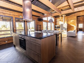 A modern kitchen with a central island, wooden cabinetry, and a large window providing a view of the outdoors. - Villa midnight sun by Interhome (Inari)