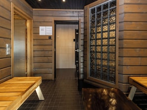 A sauna room with wooden walls, a bench, and a glass door. - Villa midnight sun by Interhome (Inari)