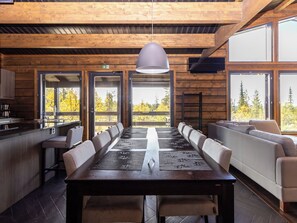 A long dining table with chairs, a sofa, and a television on the wall. - Villa midnight sun by Interhome (Inari)