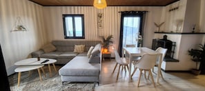 A modern living room with a grey sofa, a dining table with chairs, a small coffee table, and a fireplace. - Chalet L'Appel giettes (Les Giettes)