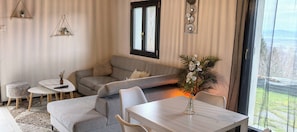 En hyggelig stue med en grå sofa, et lille rundt bord og en vase med blomster.