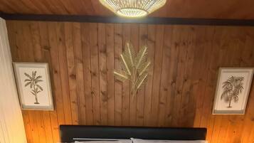 Een bed met witte beddengoed, een houten hoofdeinde en twee wandlampen.