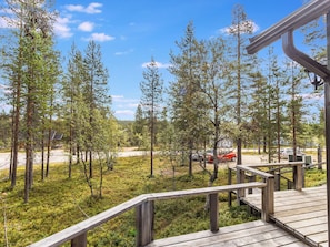 Eine Holzterrasse mit Blick auf ein bewaldetes Gebiet und eine Straße mit geparkten Autos.