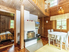 Ein Holzblockbau-Innenraum mit Kamin, Esstisch und Stühlen.