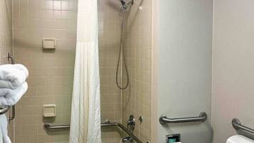 Un baño con bañera, ducha, barras de apoyo, toallero y retrete.