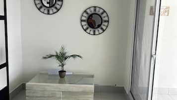 Ein Zimmer mit zwei Wanduhren, einer Topfpflanze auf einem Glastisch und einer Schiebetür.