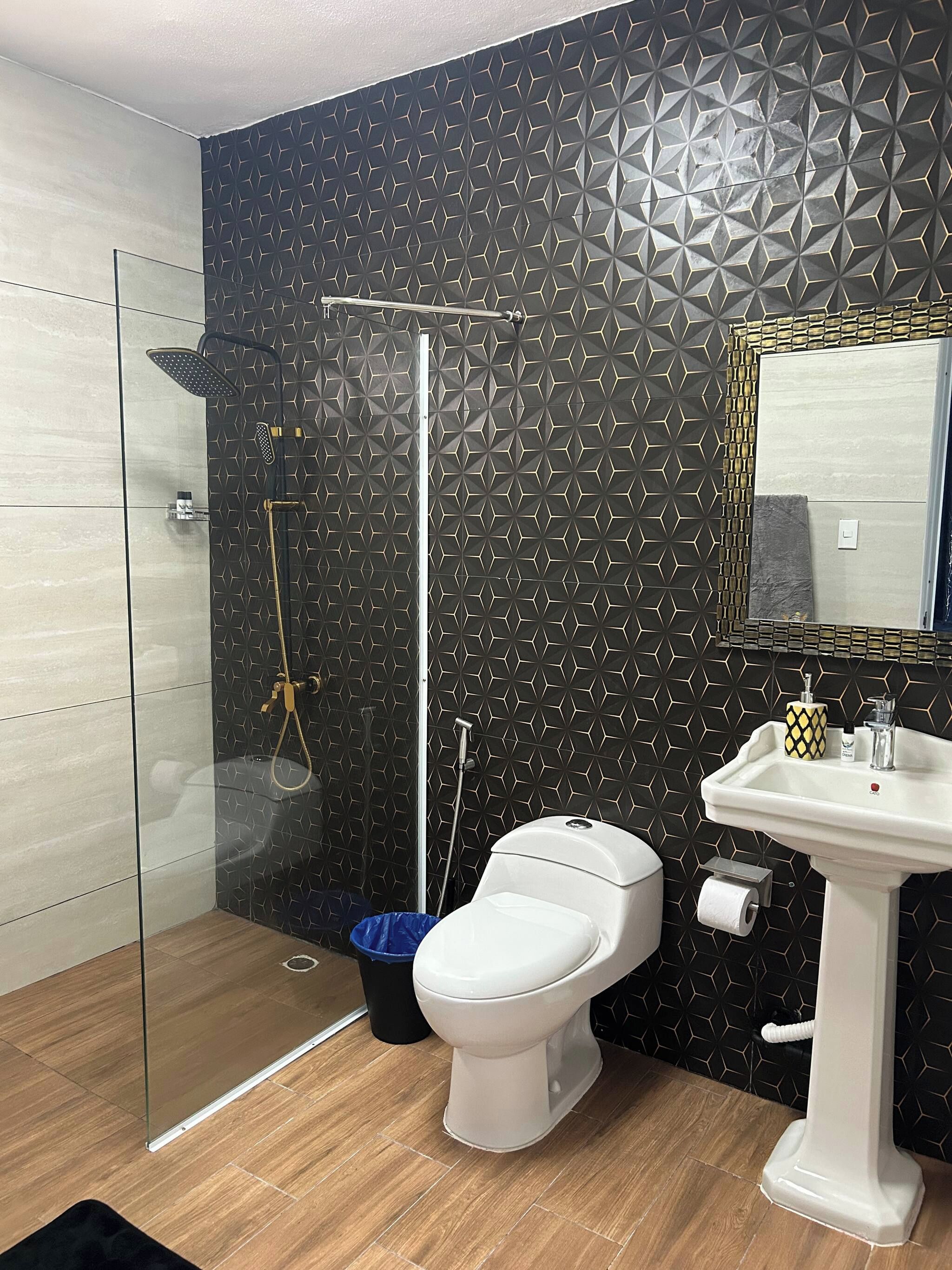 Ein Badezimmer mit Duschkabine, Toilette und Waschbecken mit Spiegel.