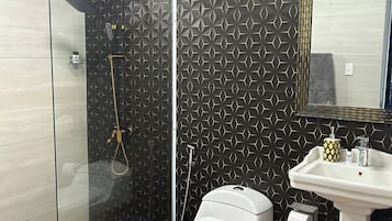 Ein Badezimmer mit Duschkabine, Toilette und Waschbecken mit Spiegel.
