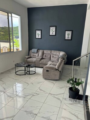 A living room with a sectional sofa, a small round table, and a potted plant.