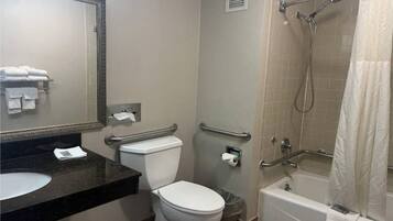 Une salle de bain d’hôtel standard, équipée d’un lavabo, de toilettes et d’un espace douche.
