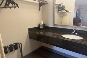 A bathroom with a sink, mirror, towel rack, and a bottle of hand sanitizer.