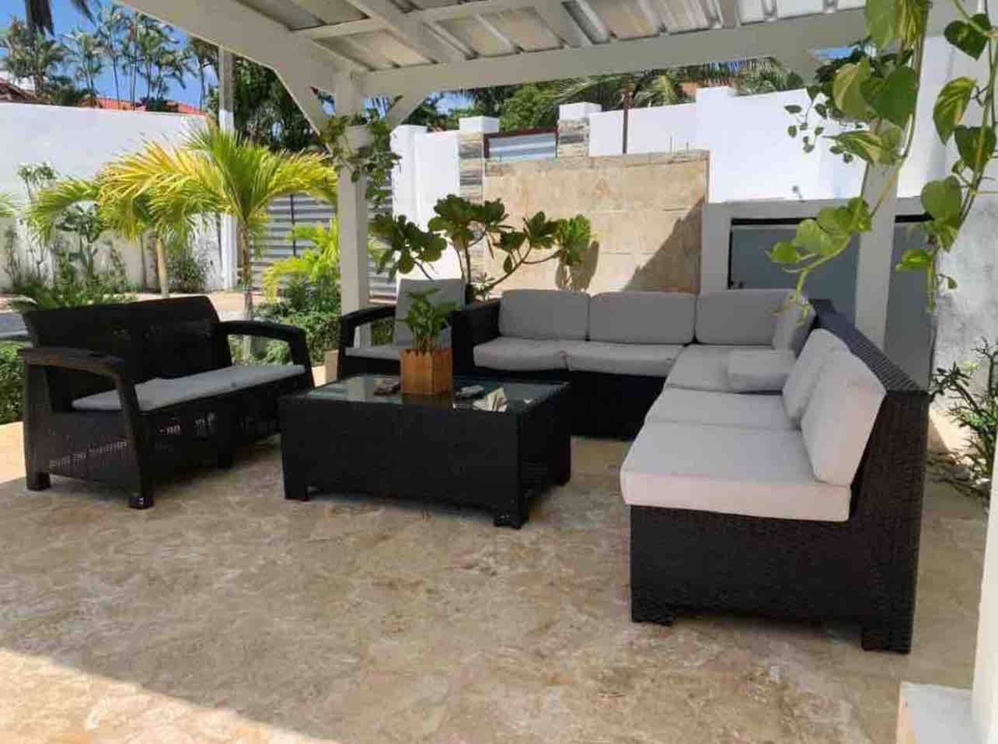 Un espace extérieur aménagé avec un canapé, deux fauteuils et une table basse.