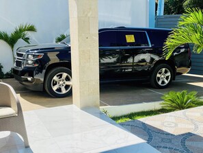 Ein schwarzer SUV steht auf einer Auffahrt mit einer gefliesten Terrasse und einer weißen Mauer.