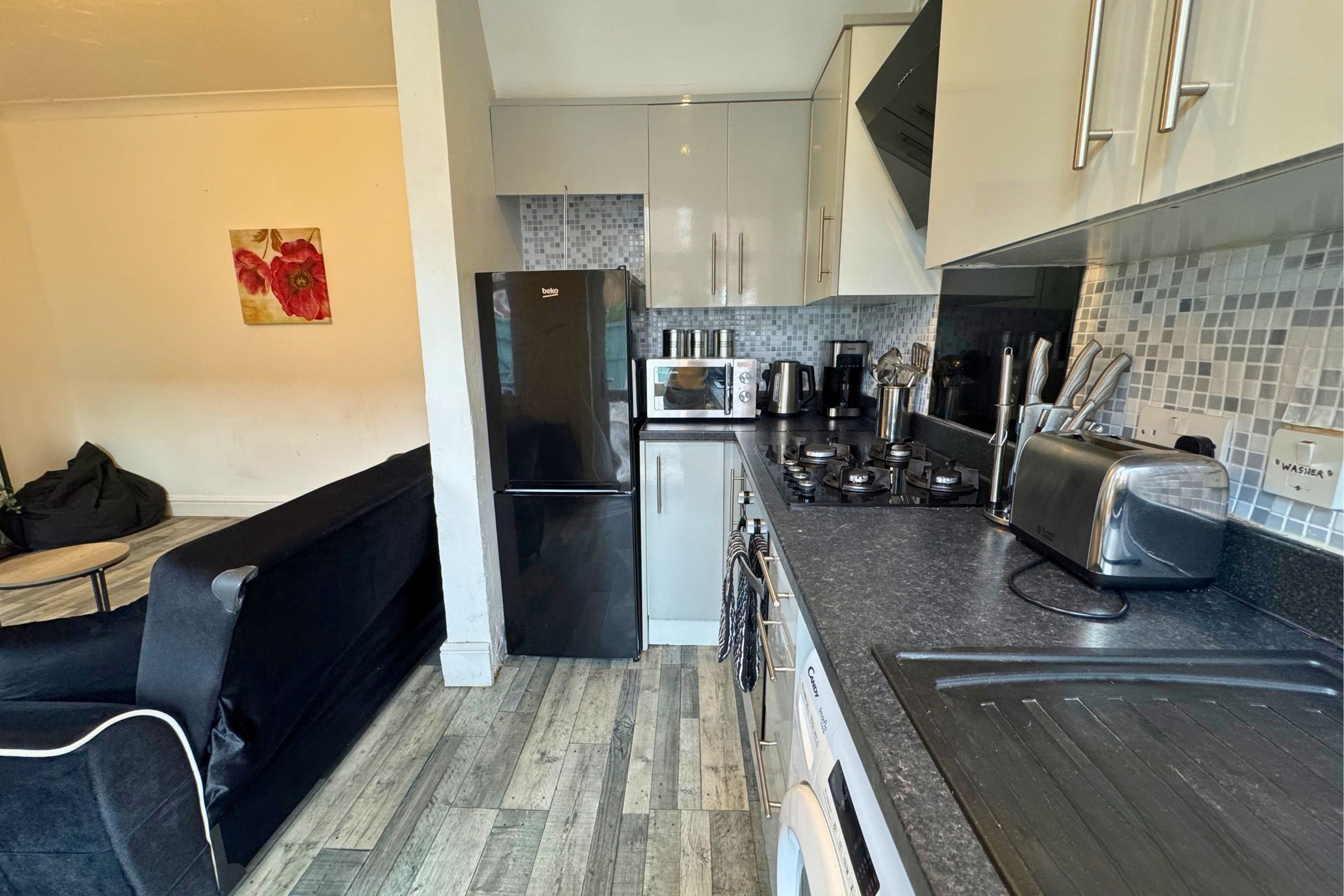 A modern kitchen with a black refrigerator, a microwave, a toaster, and a kettle.