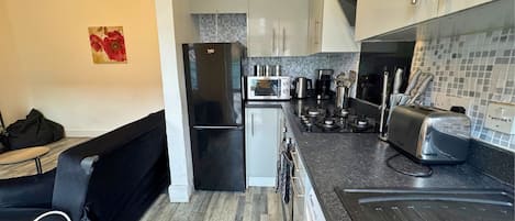 A modern kitchen with a black refrigerator, a microwave, a toaster, and a kettle.