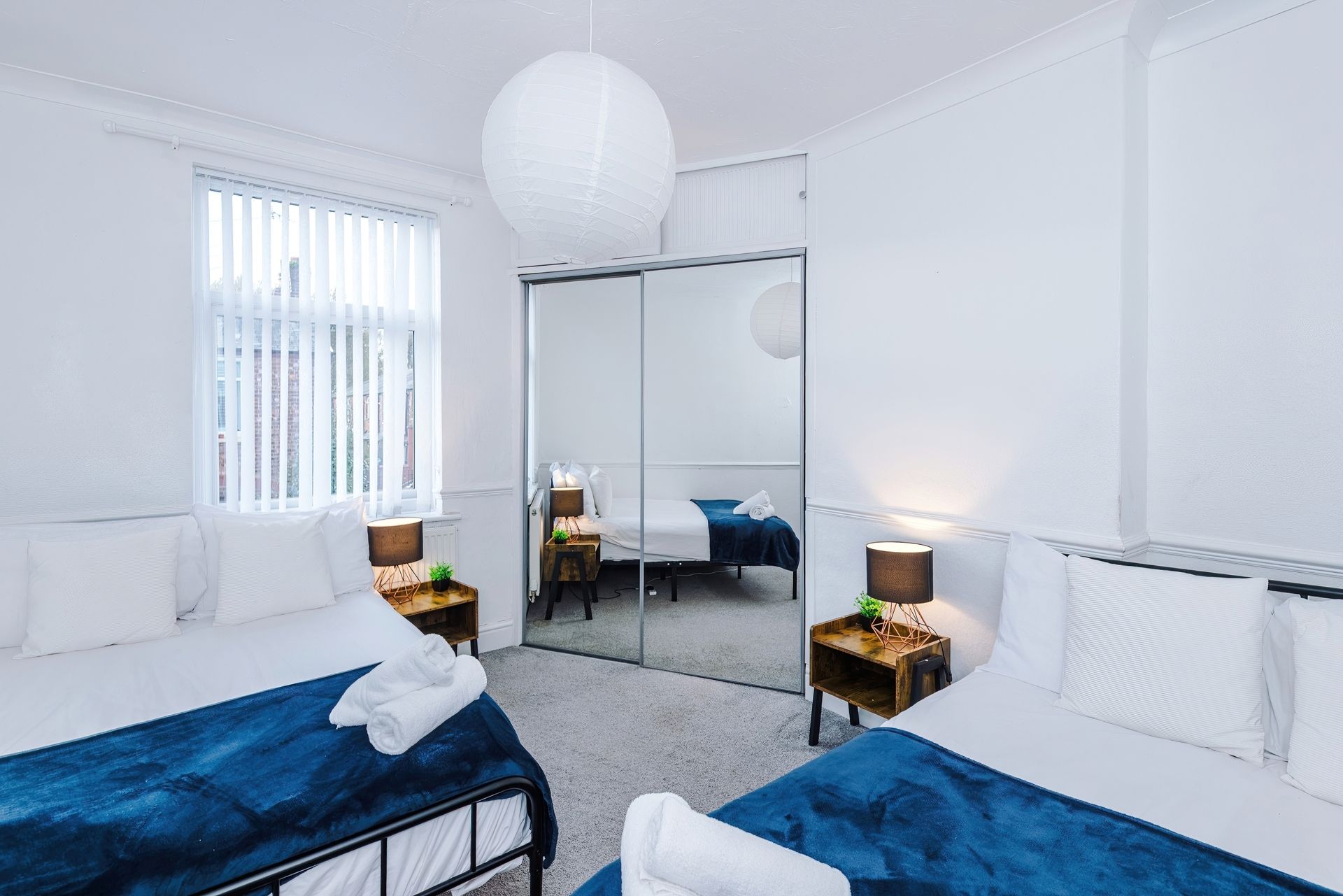 Ein Hotelzimmer mit zwei Betten, einem großen Spiegel und Blick auf die Stadt durch das Fenster.