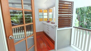 A room with a wooden door, a white cabinet, a mirror, and a view of greenery outside.