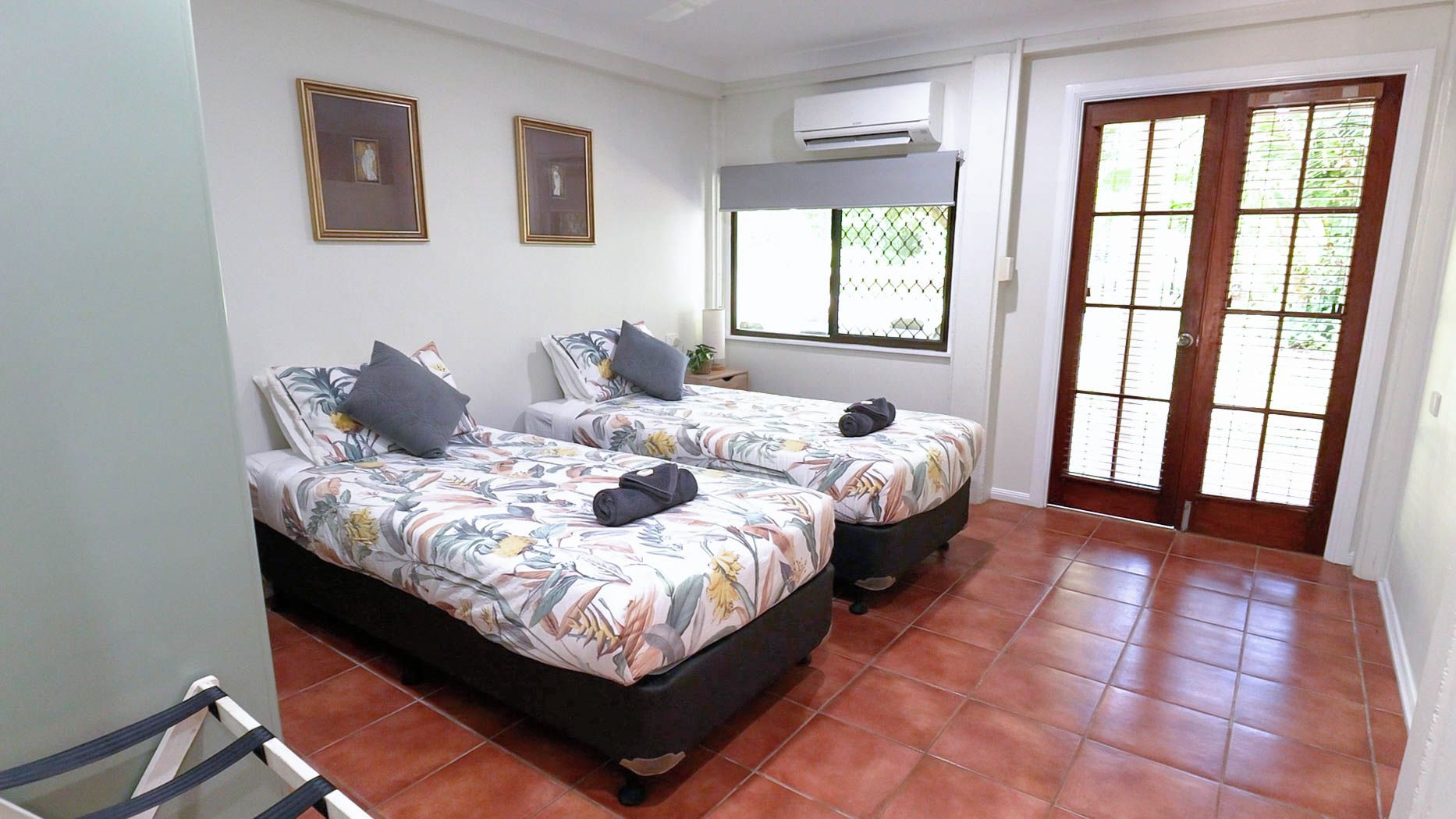 A room with two beds, a window with a view, and an air conditioning unit.