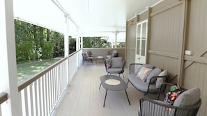 Eine überdachte Veranda mit Sitzgelegenheit, einschließlich einer Couch und Stühlen sowie einem kleinen Tisch.