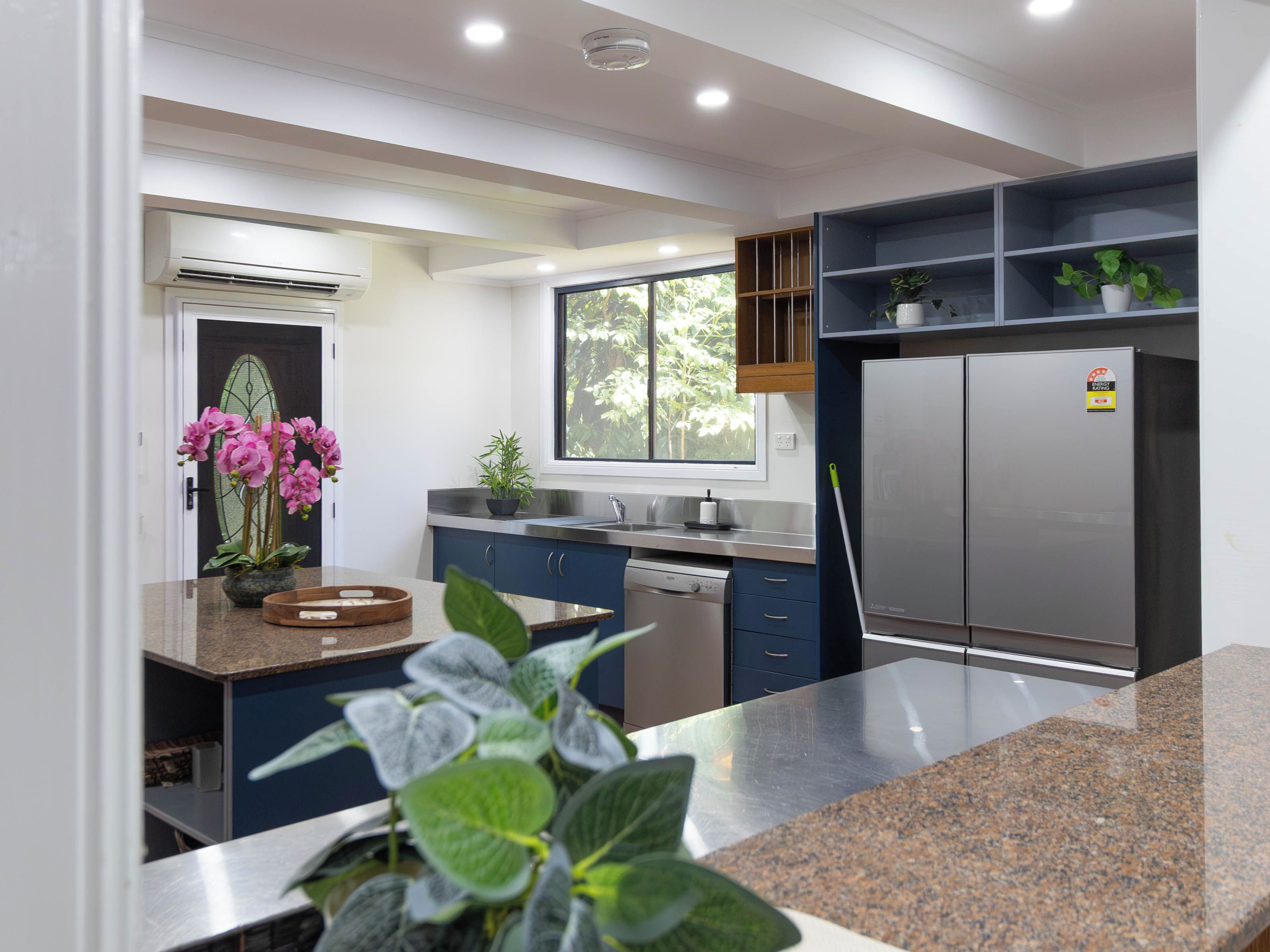 A modern kitchen with a built-in dishwasher, a stainless steel refrigerator, and a window providing natural light.