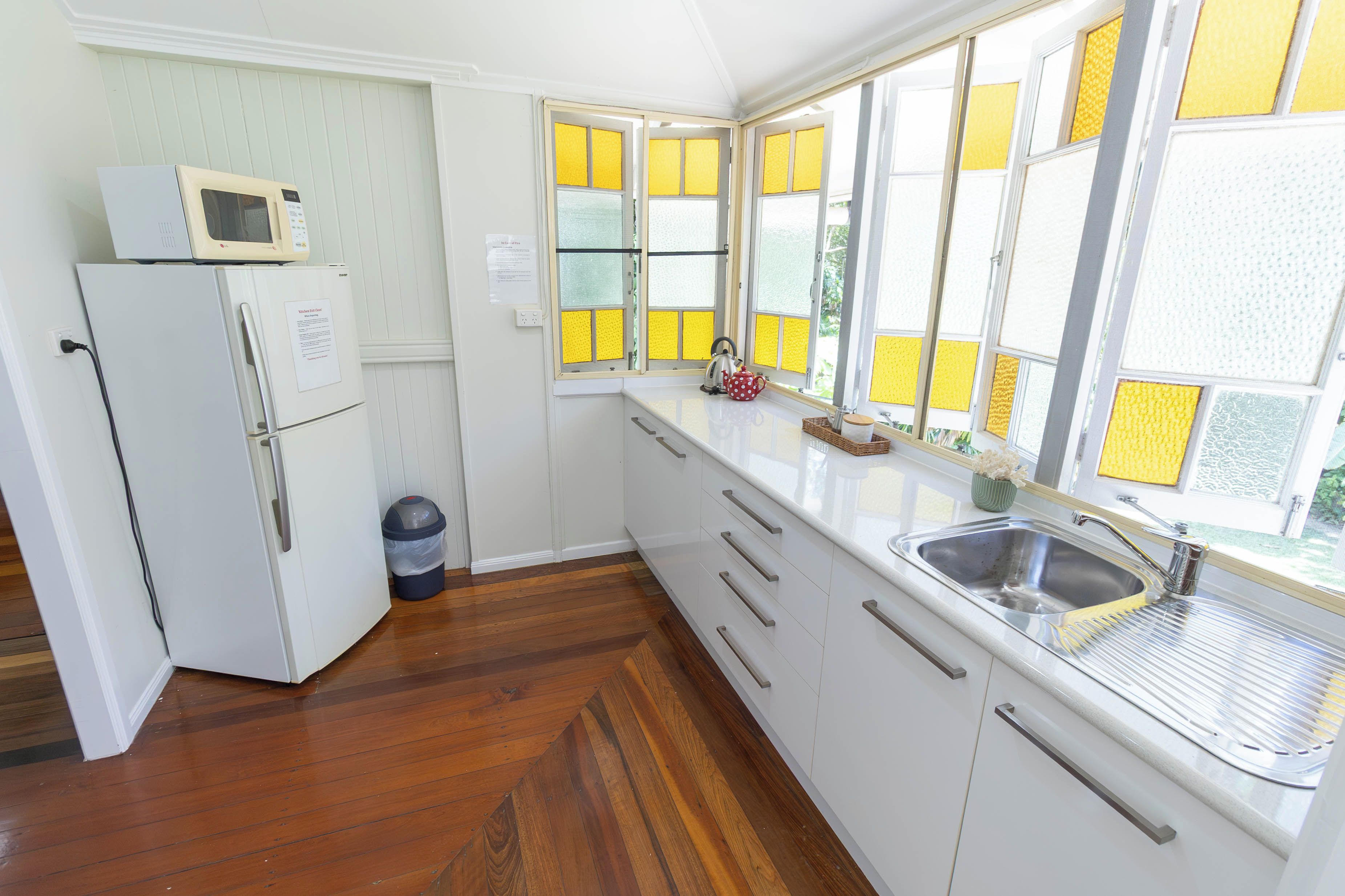 A compact kitchen with a refrigerator, microwave, and a sink.