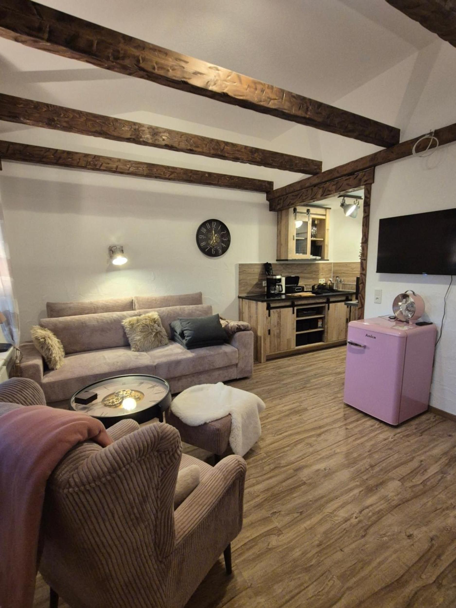 Ein gemütliches Wohnzimmer mit einer Couch, einem kleinen Tisch und einem pinken Kühlschrank.