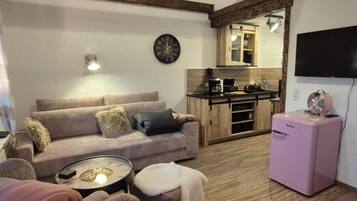 Ein gemütliches Wohnzimmer mit einer Couch, einem kleinen Tisch und einem pinken Kühlschrank.