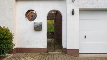 Ein Gebäudeeingang mit Briefkasten, Metallgitter und Garagentor.