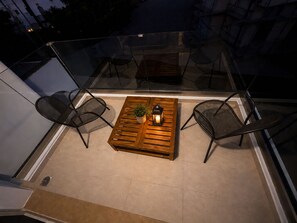 A balcony with a wooden table, two chairs, and a potted plant. - Le Palme Beach Rhodes - Bianca Villa (Charaki)