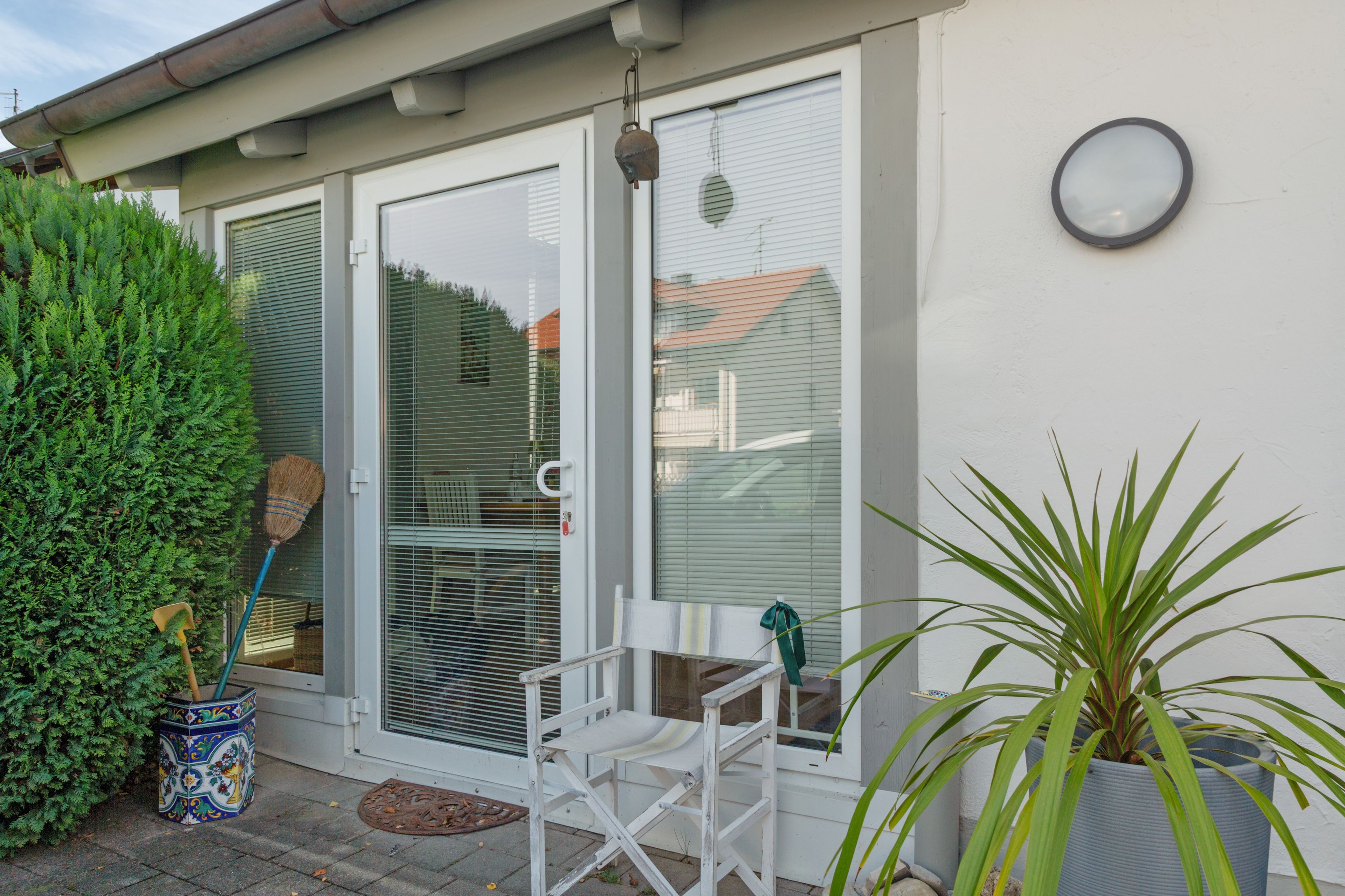 Eine Terrasse mit einem weißen Stuhl, einem Blumentopf und einem Dekoelement auf dem Boden.