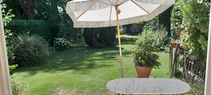 Ein Garten mit einem runden Tisch und einem Sonnenschirm.
