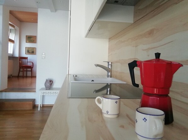 Eine Küche mit einer Holzausziehtheke, einer roten Kaffeekanne und zwei weißen Tassen mit blauen Mustern.