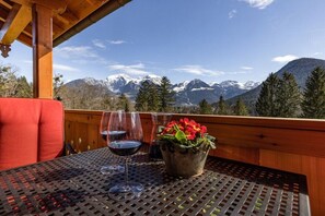 A table with two wine glasses and a potted plant on a balcony with a mountain view. - Morgenstern Mountain Farm Schoberlehen (Bischofswiesen)