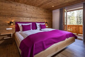 A wooden-paneled room with a large bed, two bedside tables, and a view through a sliding door to an outdoor deck. - Morgenstern Mountain Farm Schoberlehen (Bischofswiesen)