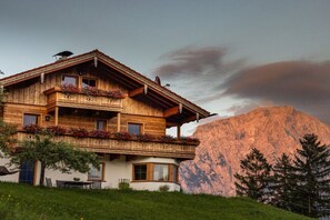 A wooden chalet with a balcony, a mountain backdrop, and a clear sky. - Morgenstern Mountain Farm Schoberlehen (Bischofswiesen)